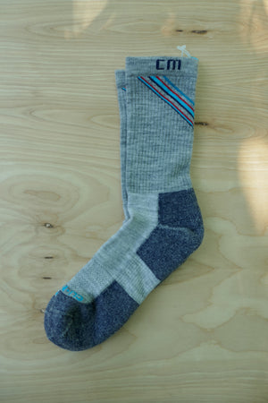 Climatesox.com CLIMATES (rebranding as E-Zmates) Men's Linkable Merino Wool Light Hiking Crew Sock flat lay on natural wood surface showing heathered gray fabric with navy, red, and teal stripe detail